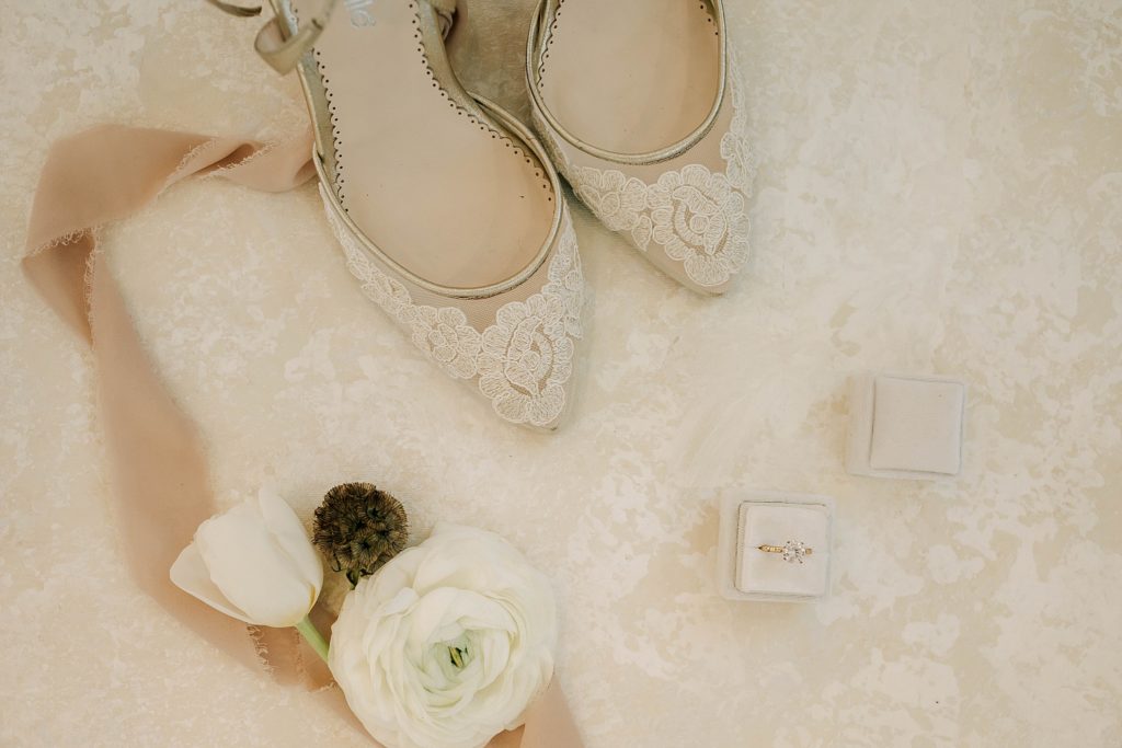 bride details in a flat lay, including shoes, florals, wedding ring and ribbon on the wedding day in idaho falls.