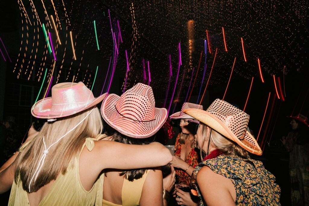 girls dancing with colorful cowgirl hats at a diamond cross ranch wedding taken by adrian wayment.