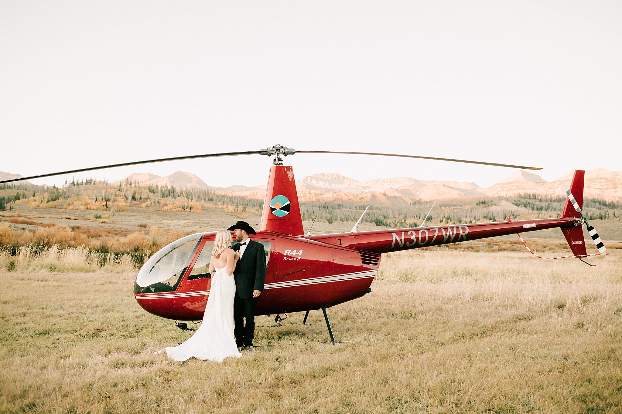 bride and groom standing in front of a helicopter after their jackson hole elopement.