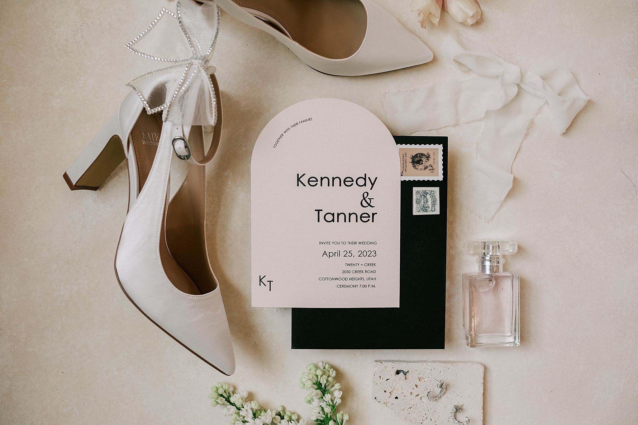 flat lay including wedding details such as bride shoes, perfume and the wedding invitation.