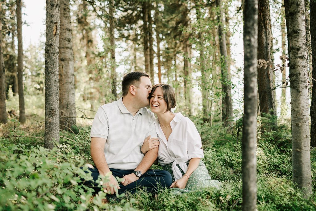 boy kissing girl at colter bay in the trees taken by jackson hole engagement photographer adrian wayment photo