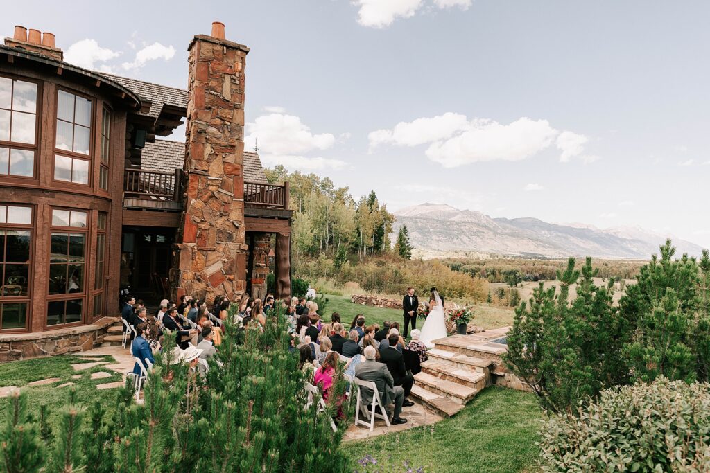 bride and groom during the ceremony with their guests seated during their jackson hole destination wedding taken by adrian wayment.