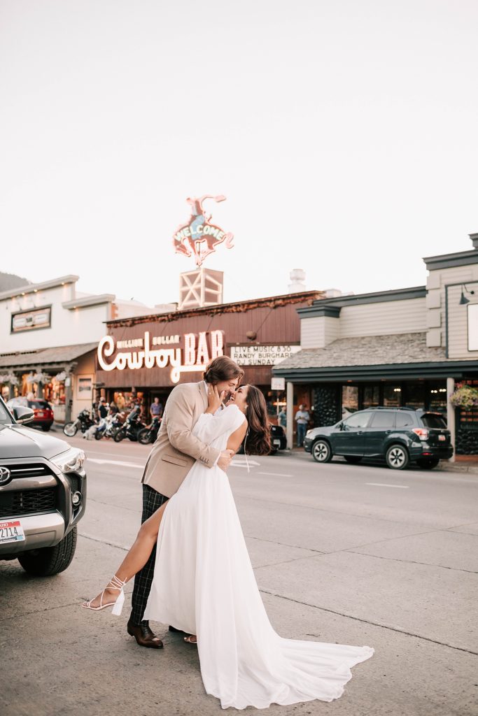 bride and groom in front of the cowboy bar in jackson hole coming in for a kiss.