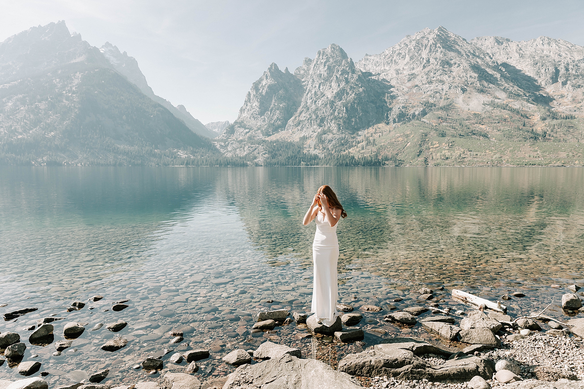 a bride standing next to Jenny Lake after her Wyoming elopement in Jackson Hole captured by adrian wayment.