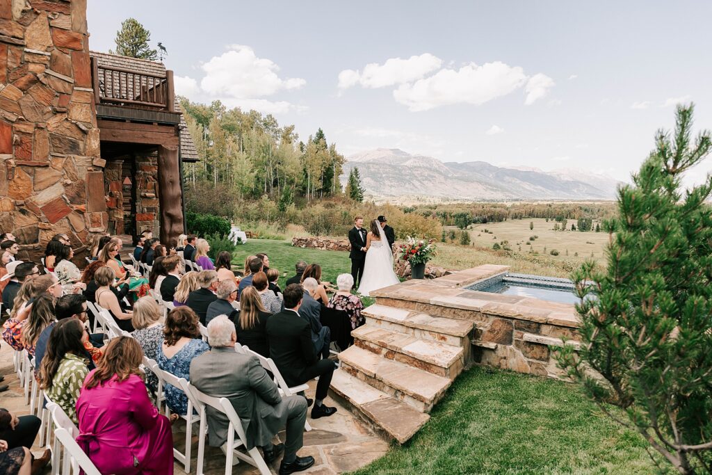 bride and groom during the ceremony with their guests seated prior to their cloudveil jackson hole wedding reception.