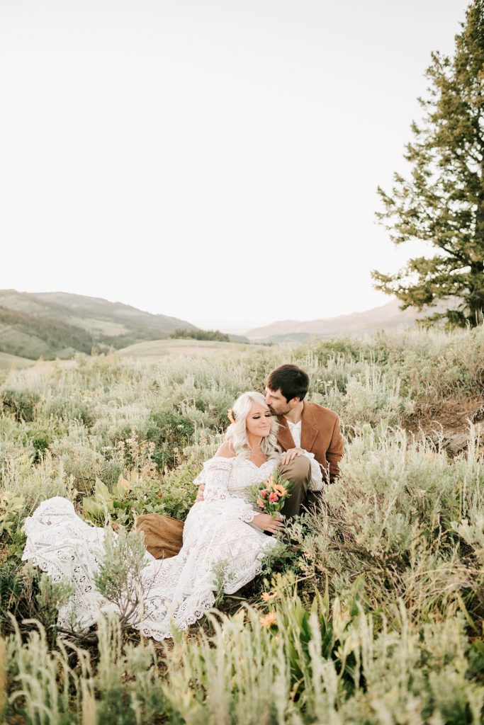 bride and groom sitting in the shrubs after their wyoming wedding