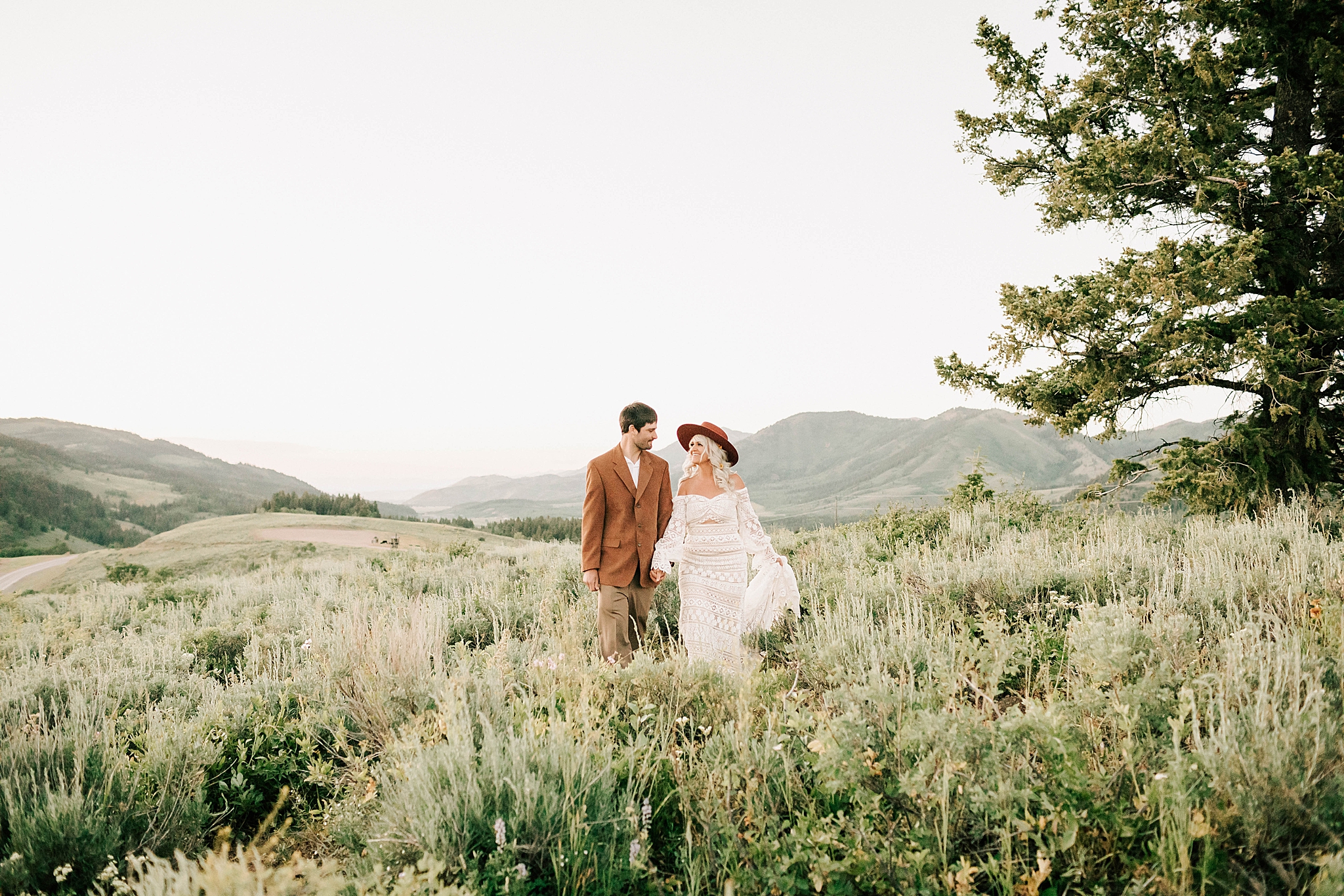 bride and groom walking through a meadow near jackson lake lodge wedding venue by adrian wayment photo
