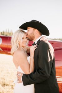 groom kissing bride right next to their getaway helicopter after their brush creek ranch wedding.