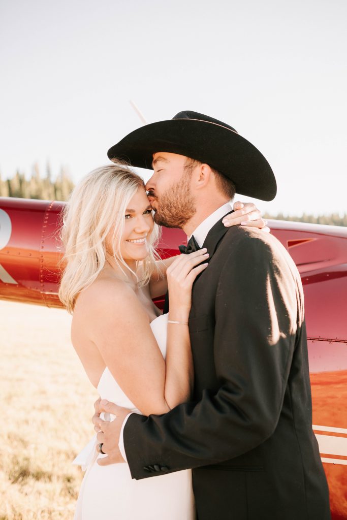 groom kissing bride outside of a red helicopter just before their jackson hole helicopter tour.