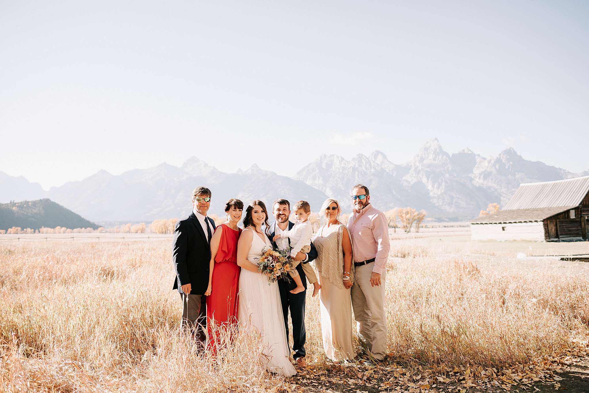 the whole group at an intimate moulton barn wedding in grand teton national park smiling at the camera.