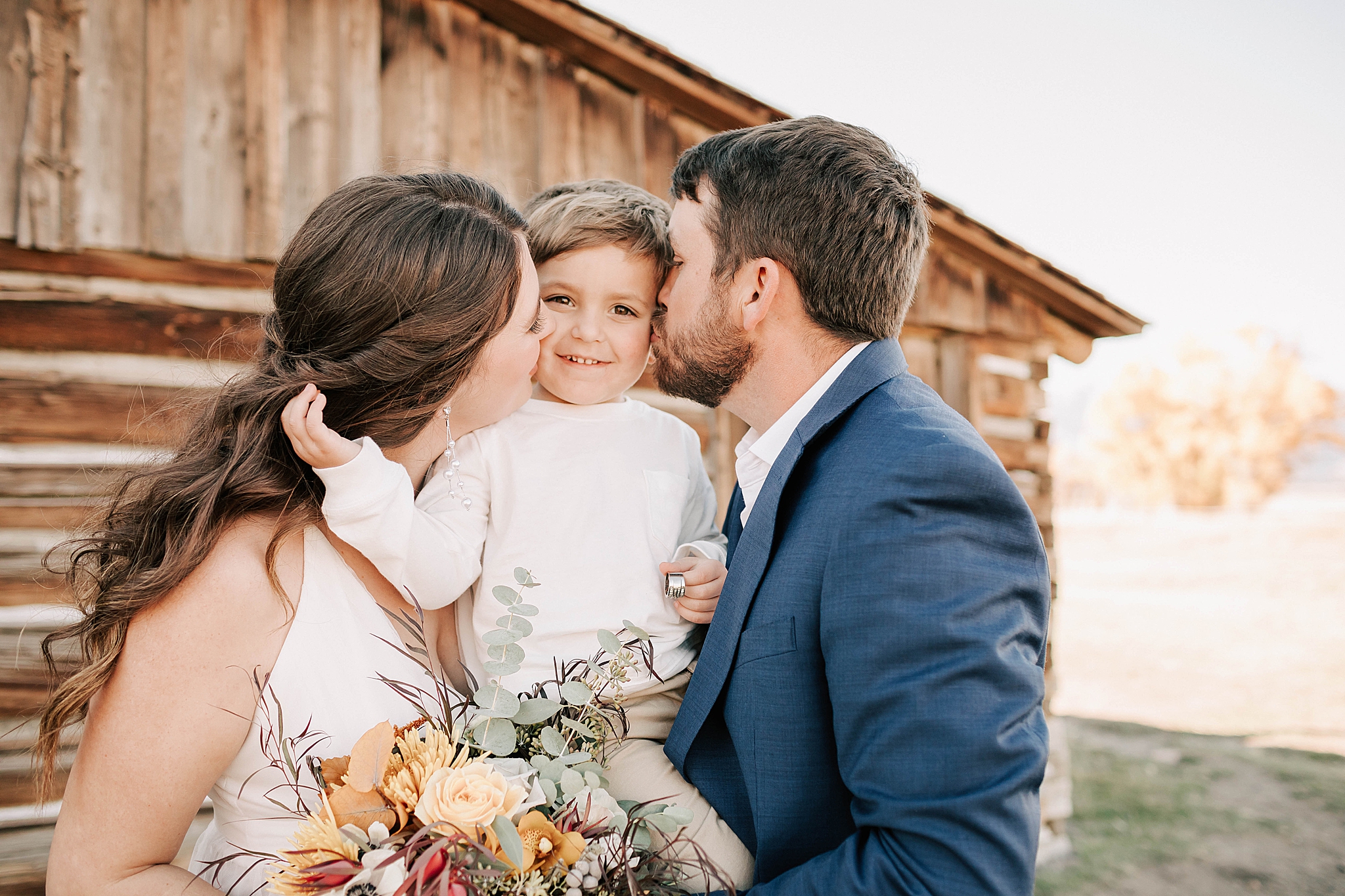 bride and groom kissing their 3 year old after their intimate ceremony. photo taken by adrian wayment photo.
