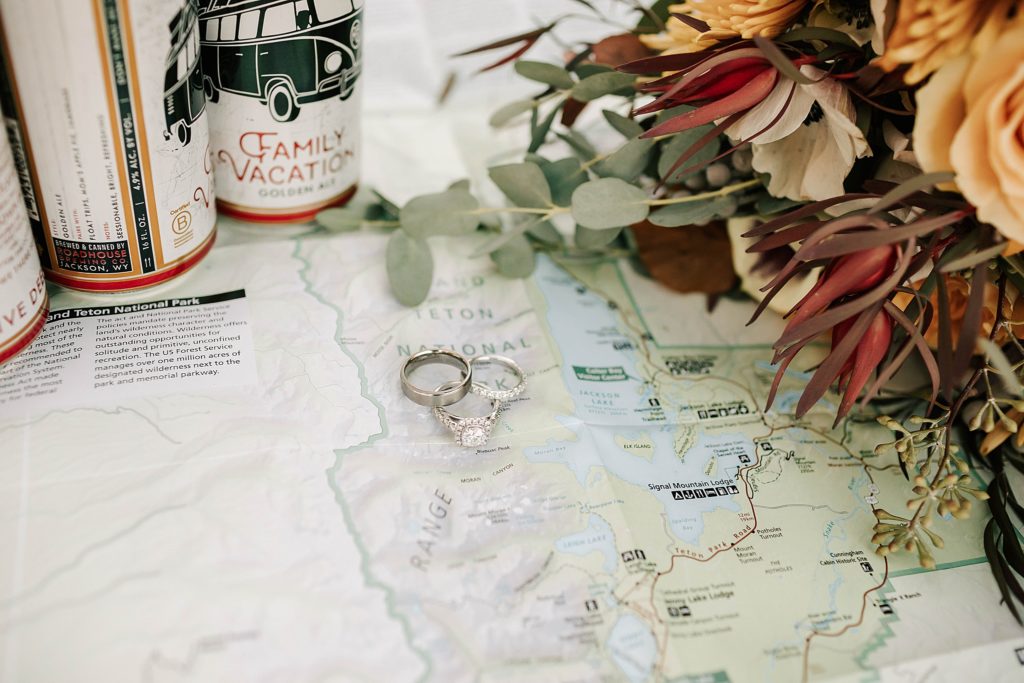 bride and grooms wedding rings, bouquet and local Jackson Hole beer on a Grand Teton map for a detail shot.