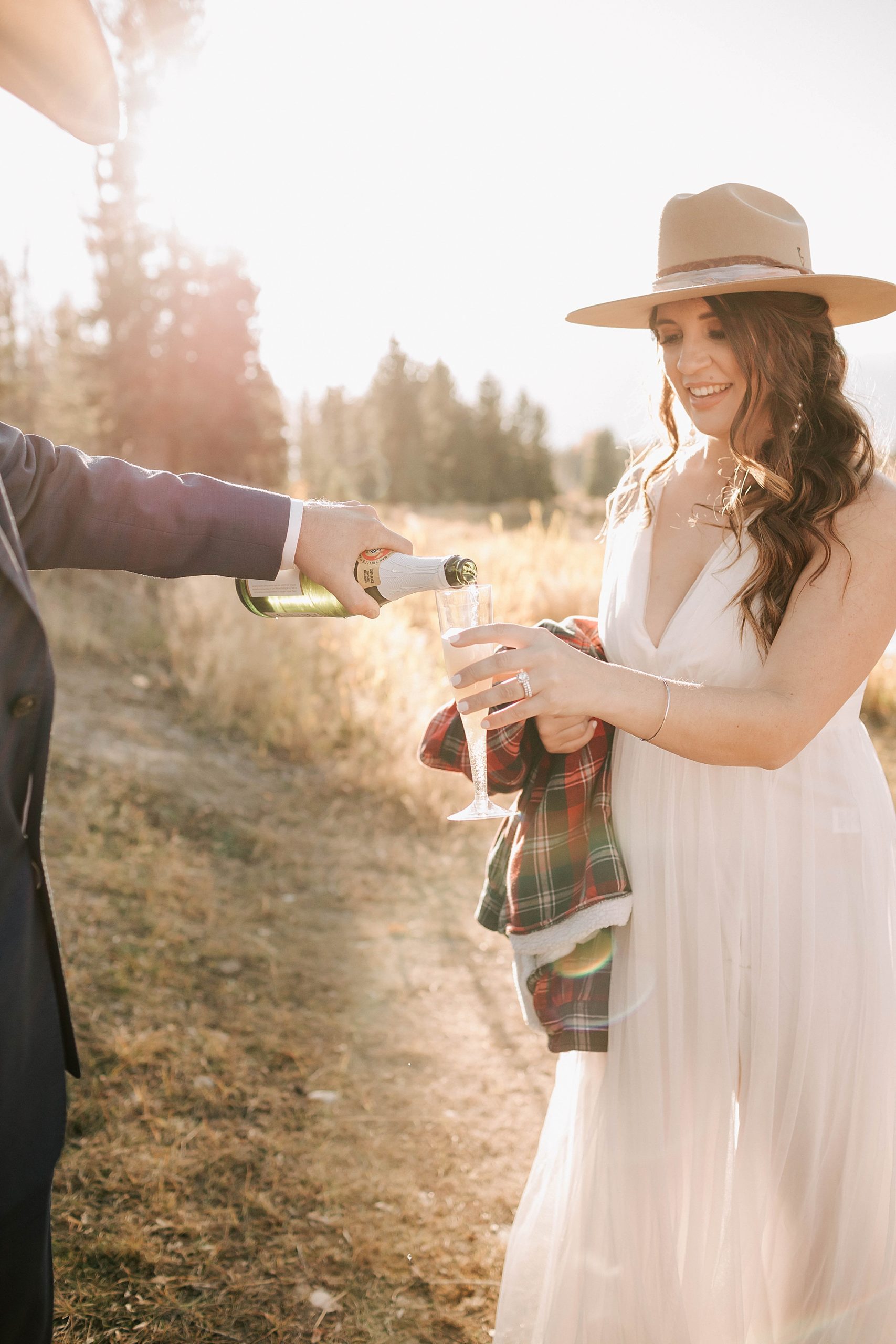Groom pouring sparkling cider for his bride in celebration of their beautiful Moulton Barn wedding in October.