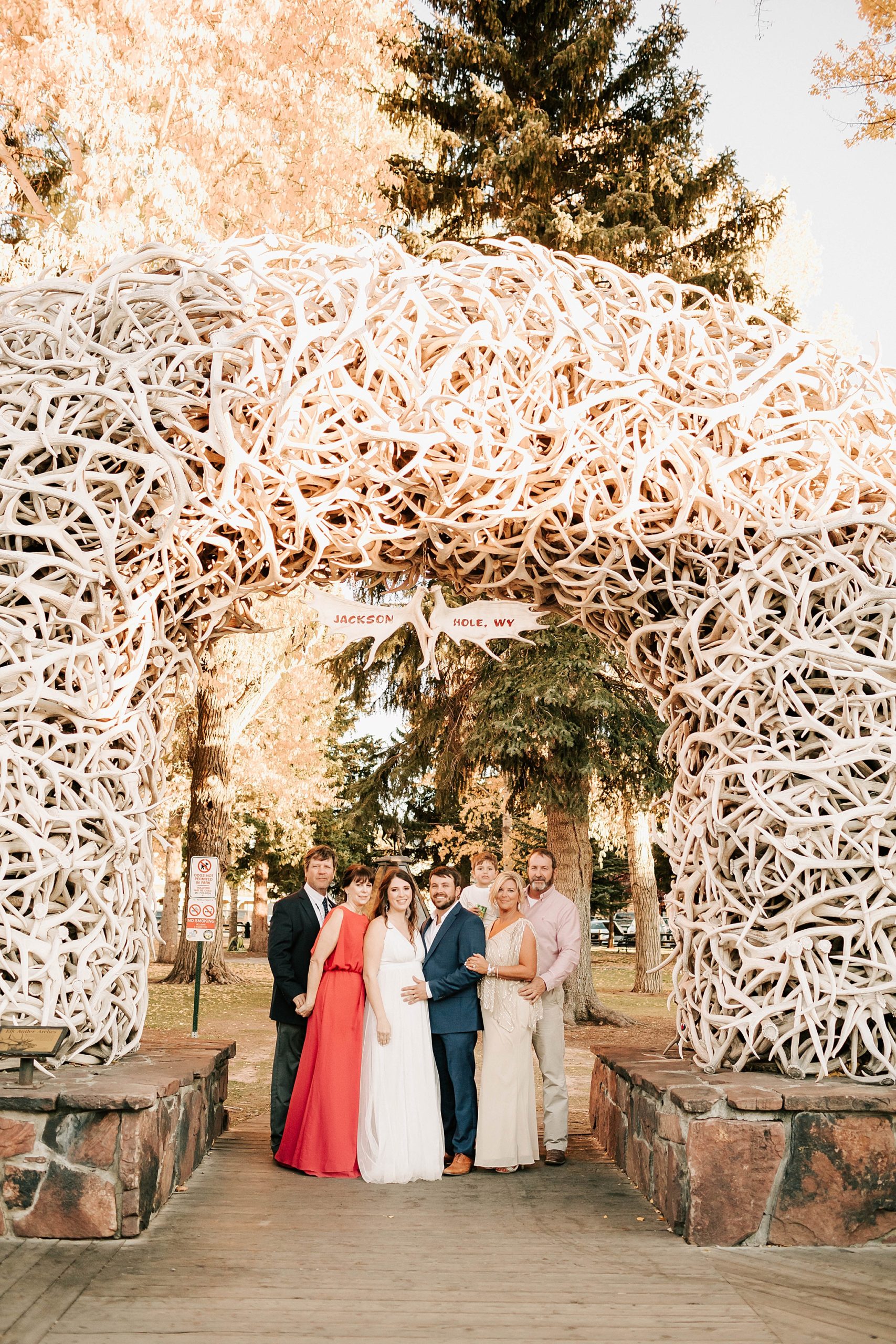 bride and groom with their parents and their child at an arch in Town Square after their intimate Moulton Barn wedding.