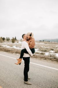 boy holding his fiance on the road during their adventurous engagement session at the snake river overlook.