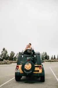 engaged boy and girl sitting on top of their jeep at their snake river overlook engagement session.