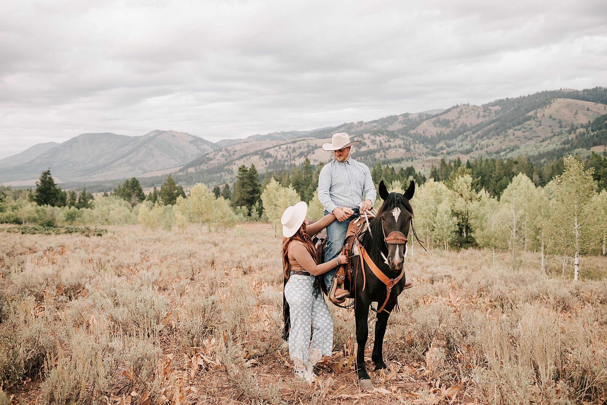 engaged couple taking western engagement photos in wyoming with a horse.