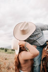 engaged couple kissing with their hats on during their western engagement photoshoot taken in western wyoming.