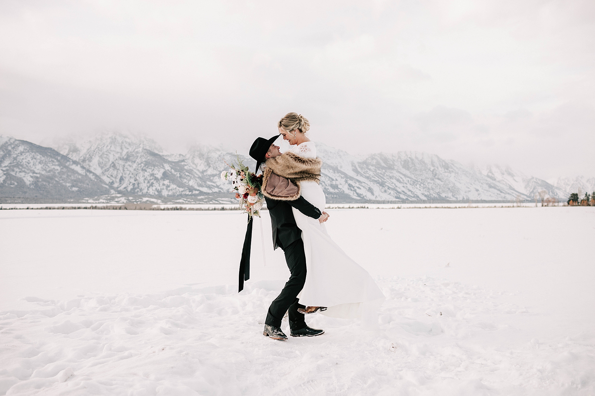 groom holding bride in the snow at their jackson hole winter wedding in grand teton national park.